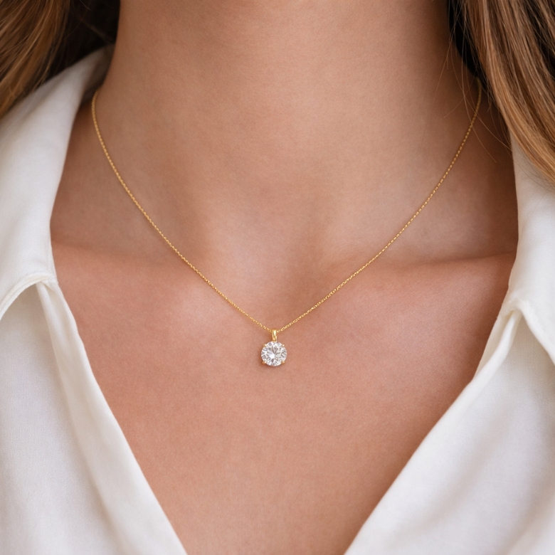 Close-up of a woman wearing a Collana Punto Luce with Pietra Luminosa Incastonata in Acciaio Dorato, showcasing its gold chain and sparkling stone.