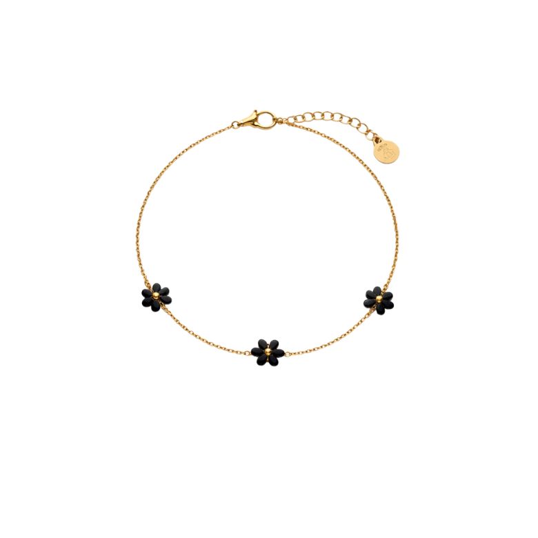 Bracciale acciaio dorato con fiori neri smaltati indossato su un braccio.
