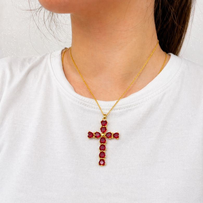 Collana con croce di cuori rossi indossata. Gioiello elegante, argento.