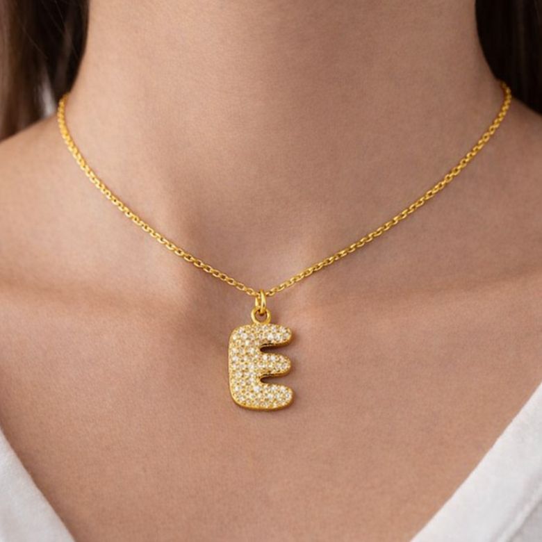 Collana con pendente lettera E in acciaio dorato e strass indossata.
