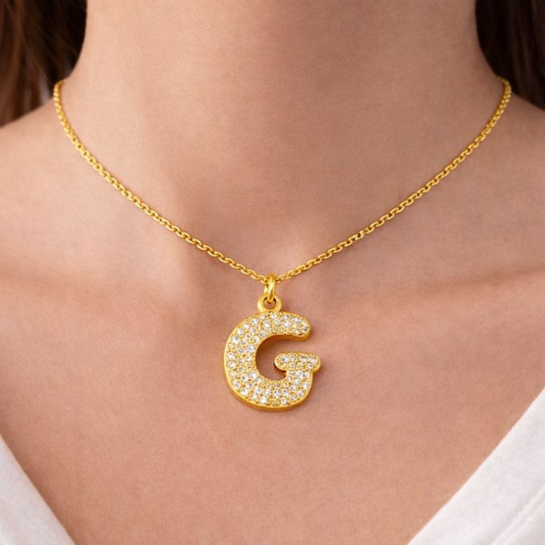 Collana con pendente lettera G in acciaio dorato e strass. Gioiello elegante e personalizzato.